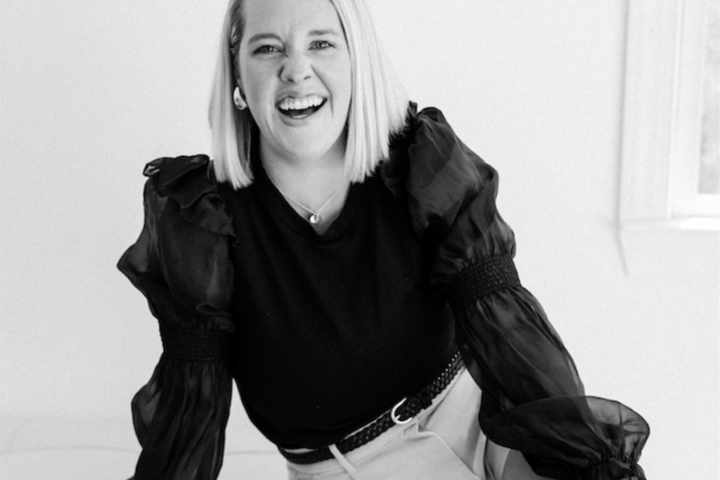 Image of a luxury wedding photographer laughing at the camera - she is wearing a black blouse
