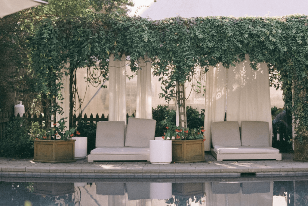Image of some loungers by a pool, surrounded by foliage. Capturing the mood as part of a wedding photographer shot list.
