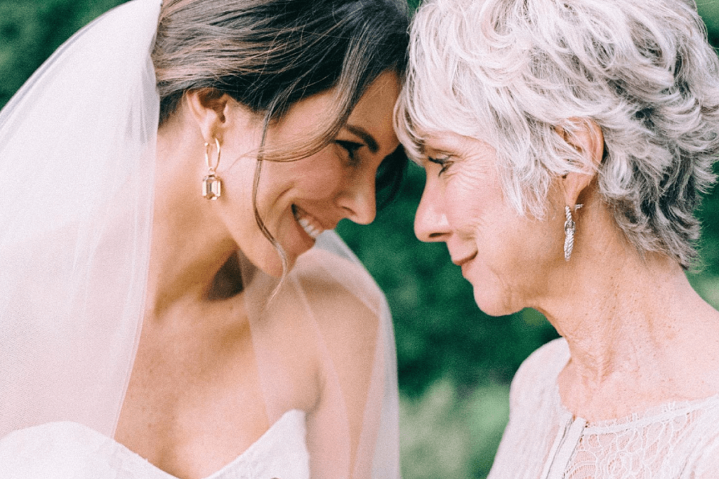 Image of a bride and her mother touching heads for an intimate moment together