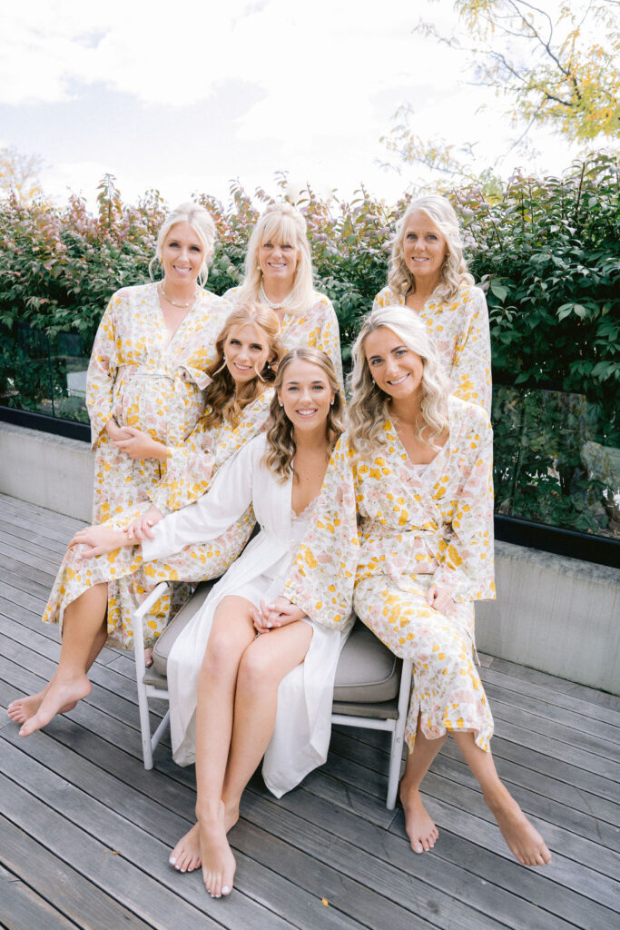Bride sitting with bridesmaids in yellow floral dressing gowns before her wedding at the Winslow, Baltimore